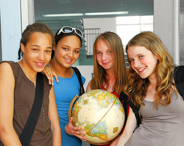 Ein Porträt von vier Mädchen, eine hält einen Globus in der Hand.