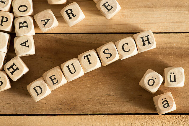 Würfel mit Buchstaben in einer Reihe, die das Wort Deutsch ergeben.